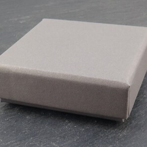 K&ouml;nnte beinhalten: Eine graue, rechteckige Box mit einer glatten, strukturierten Oberfl&auml;che.