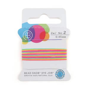 May include: A spool of Griffin 100% natural silk cord, labelled Bead Snob Dye Job, featuring a vibrant multi-coloured striped pattern in neon pink, yellow, and turquoise. The packaging indicates a length of 2M, size No. 2, and a diameter of 0.45mm.