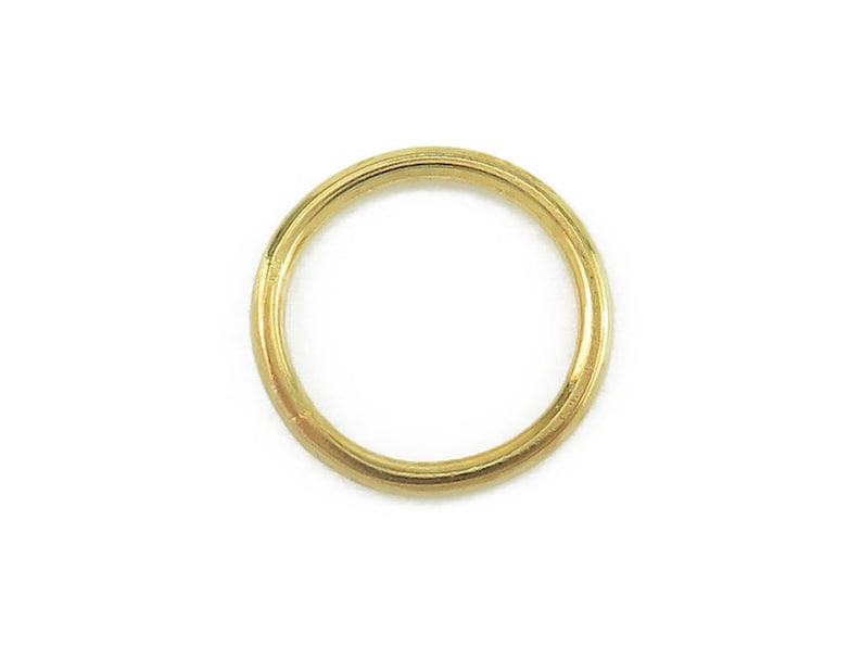 May include: A single, solid gold ring, circular in shape, set against a white background. The ring has a smooth, polished surface and a warm, yellow hue. The ring is a jewelry item.