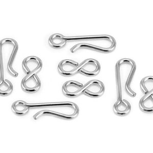 May include: A set of eight silver-toned metal jewellery findings. The findings are in the shape of a figure eight and a hook.