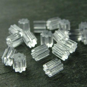 May include: A pile of clear plastic earring backs. The backs have a star-shaped design and are designed to hold earrings in place.