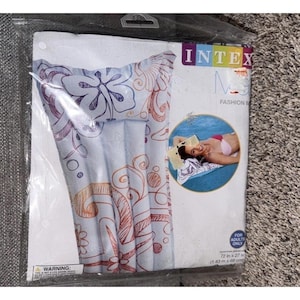 May include: An Intex brand inflatable pool float in a clear plastic package. The float is white with purple and orange floral and swirl patterns. The packaging includes the text Intex, Fashion Mat, and For Adults Only, with dimensions of 1.83 m x 69 cm.