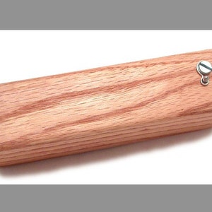 May include: A wooden box with a hinged lid and a metal latch. The box is made of light brown wood with a grain pattern.