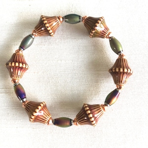 May include: A brown and white ceramic bead bracelet with copper and iridescent green spacers.