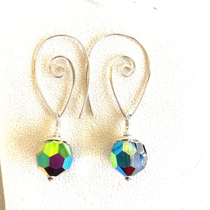May include: A pair of silver dangle earrings with a green and blue iridescent faceted glass bead on each earring.