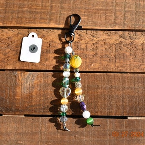 Joyería para monedero hecha a mano con detalles brillantes, herrajes negros, cordón de cuero genuino, cuentas y dijes de vidrio amarillo y verde, espaciadores plateados, cuentas de vidrio con forma de rueda.