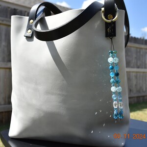 Monedero de cristal hecho a mano con cuentas brillantes y herrajes negros únicos y genuinos, cordón marrón de cuero genuino, color azul marino y turquesa.