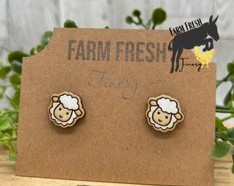 May include: A pair of wooden sheep earrings on a brown card with the text "Farm Fresh Finery".