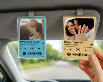 May include: Two clear acrylic car accessories with song details. One is light blue with "I Wanna Be Yours" by Arctic Monkeys. The other is yellow with "Better Together" by Luke Combs. Both have a photo, song details, and a Spotify-style waveform.