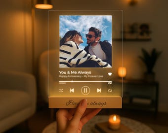 May include: A personalized acrylic photo frame with a wooden base. The frame displays a couple's photo and the text "You & Me Always." The base has the inscription "I love you always." The frame is illuminated with a warm glow.