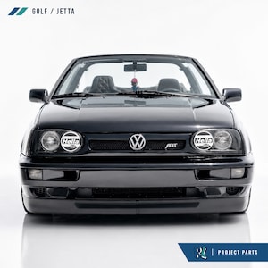 Puede incluir: Un Volkswagen Golf o Jetta descapotable negro visto desde el frente. El vehículo cuenta con una parrilla delantera con el emblema de Volkswagen, una insignia ABT y dos luces auxiliares redondas Hella. El texto GOLF / JETTA aparece arriba.