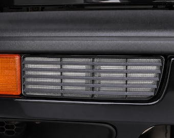 May include: A black automotive bumper assembly featuring a rectangular clear lens fog light with horizontal slats and an adjacent orange side marker light. The text GOLF / VENTO / JETTA is visible at the top, and PROJECT PARTS is at the bottom.