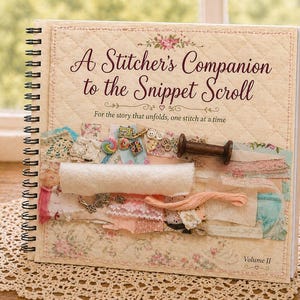 May include: A spiral-bound book titled "A Stitcher's Companion to the Snippet Scroll" with floral and quilted cover design. The book features a collection of fabric scraps, buttons, and a wooden spool. The text reads "For the story that unfolds, one stitch at a time."