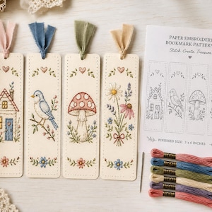 May include: Four paper bookmarks with embroidered designs of a house, a blue bird, a mushroom, and wildflowers, each with a fabric ribbon topper. Includes a printed pattern sheet labeled Paper Embroidery Bookmark Patterns and six embroidery floss skeins.