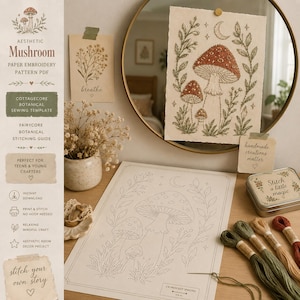 Peut inclure: Un kit de broderie sur papier présentant un motif de champignons avec un croissant de lune et du feuillage. L'ensemble comprend un modèle imprimé, un échantillon brodé fini, quatre écheveaux de fil et une petite boîte en métal.