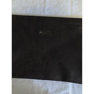 May include: A dark brown rectangular clutch with a textured, faux-leather finish. The surface features a subtle, embossed rectangular logo patch centered near the top edge, displaying the word 'FNSM' in a stylized, slightly worn silver font.