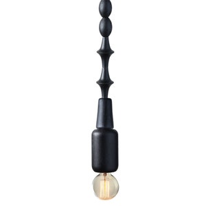 Black wooden pendant light with geometric sculptural design and Edison bulb, creating a bold, industrial statement in modern interiors