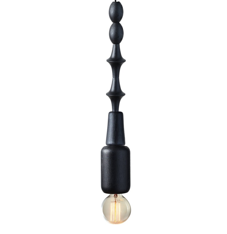Black wooden pendant light with geometric sculptural design and Edison bulb, creating a bold, industrial statement in modern interiors
