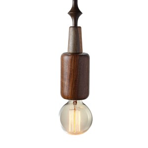 Dark wood pendant light featuring unique sculptural lines and Edison bulb, adding a touch of rustic sophistication to urban loft spaces