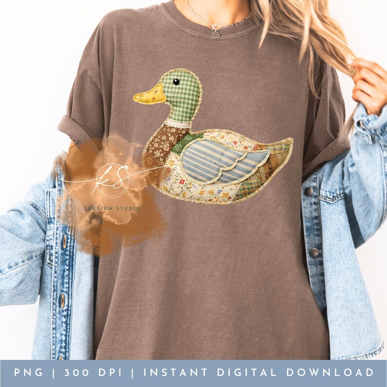 Pode incluir: Uma camiseta marrom com um design de pato em patchwork. O pato tem uma cabe&ccedil;a xadrez verde, um bico amarelo e um corpo feito de v&aacute;rios tecidos estampados. O texto na parte inferior diz "PNG | 300 DPI | DOWNLOAD DIGITAL INSTANT&Acirc;NEO".