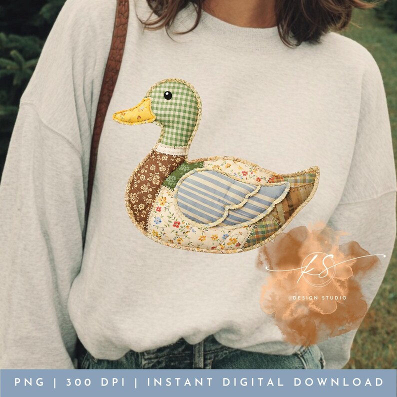 Pode incluir: Um moletom cinza com um design de pato em patchwork. O pato tem uma cabe&ccedil;a xadrez verde e branca, um bico amarelo e um corpo feito de v&aacute;rios tecidos florais e listrados. &Eacute; um download digital.