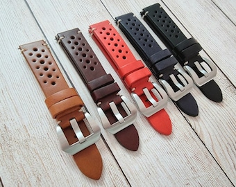 Può includere: Cinque cinturini per orologio in pelle con un design traforato e fibbie argentate. I cinturini sono di colore marrone, beige, rosso, nero e blu.