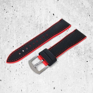 May include: Black watch strap with red stitching and a silver buckle.