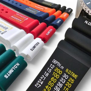 Op de afbeelding: Een close-up van een verscheidenheid aan horlogebandjes in verschillende kleuren en ontwerpen. De bandjes zijn gemaakt van siliconen en hebben de tekst "N.D.LIMITS" erop gedrukt. De bandjes zijn ook gemarkeerd met dieptemetingen in meters en N.D.TIME.