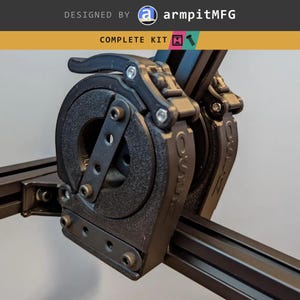 May include: A black mechanical assembly featuring a circular clamp with a lever mechanism, mounted on black aluminum extrusion rails. The text DESIGNED BY armpitMFG and COMPLETE KIT is visible at the top, along with icons of a printer and a bolt.