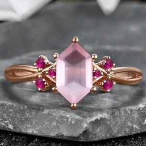 May include: A rose gold ring with a large pink gemstone surrounded by smaller red gemstones.