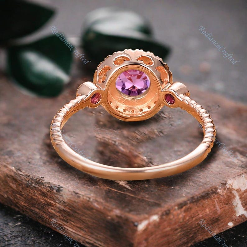 May include: A rose gold ring featuring a round purple gemstone encircled by smaller clear gemstones. The ring has a delicate, twisted band.