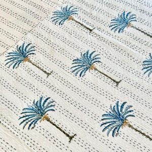 May include: White cotton fabric with a repeating pattern of blue palm trees. The fabric has a subtle texture and is perfect for a variety of crafting projects.