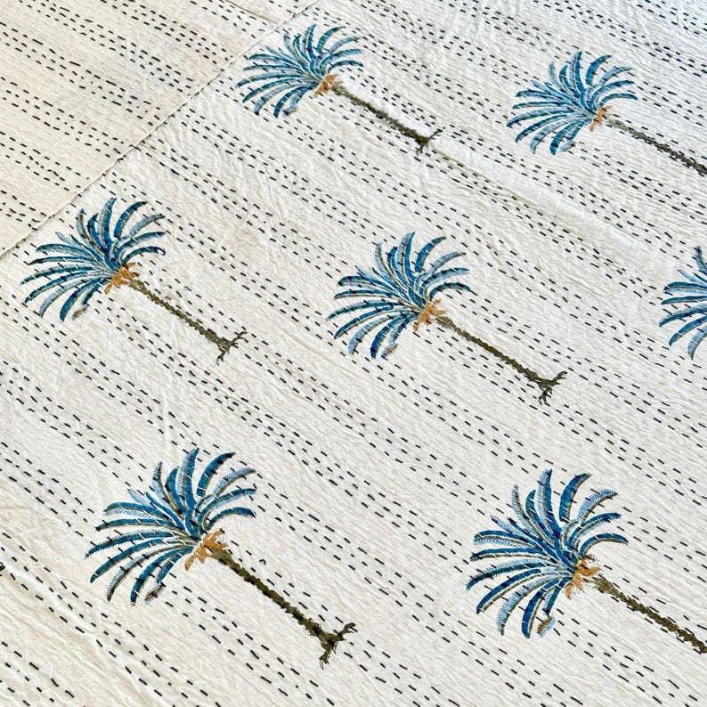 May include: White cotton fabric with a repeating pattern of blue palm trees. The fabric has a subtle texture and is perfect for a variety of crafting projects.