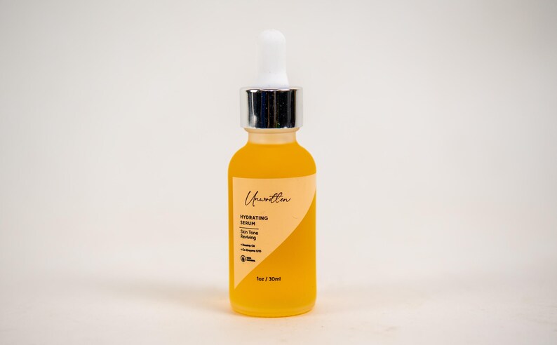 Puede incluir: Un frasco de vidrio de suero hidratante con un gotero. El frasco est&aacute; etiquetado con "Unwritten" y "Hydrating Serum". El suero es de color amarillo claro. El frasco es de 30 ml.