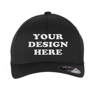 May include: Black baseball cap with the embroidered text "YOUR DESIGN HERE" in white. The cap has a curved peak and a small button on top. The cap is a solid black colour.