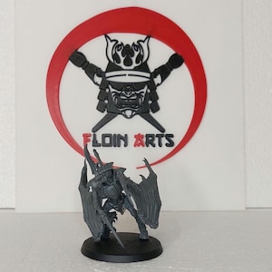 Puede incluir: Una miniatura de plástico gris de una criatura alada con una espada, de pie sobre una base negra. La miniatura no está pintada y tiene un diseño detallado.