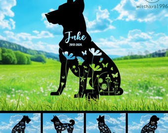 May include: Black silhouette of a dog with flowers and butterflies, the name "Jake" and the dates "2012-2024" are written on the silhouette.  The silhouette is on a green grassy background.