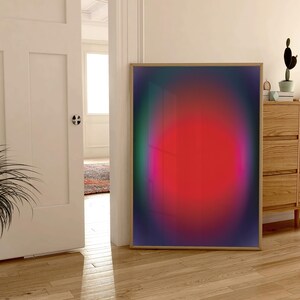 May include: A framed abstract art print with a gradient of colours, including green, purple, pink, and red. The print features a large, circular, red shape in the centre.