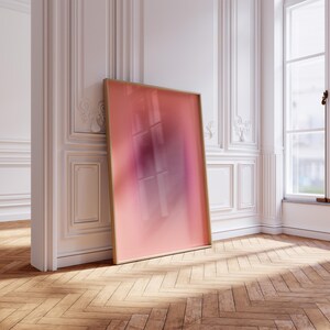 May include: A large, framed abstract painting with a pink and purple gradient. The painting is leaning against a white wall in a room with hardwood floors.