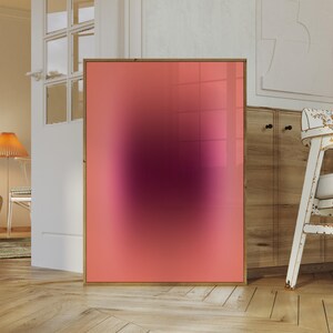 May include: A framed abstract art print with a pink to purple gradient. The print has a blurred effect, creating a soft, dreamy look.