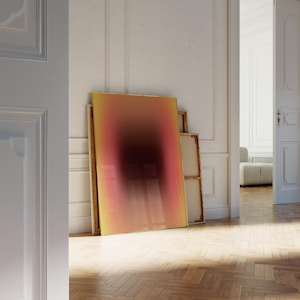 Puede incluir: Una gran pintura abstracta con un degradado de colores amarillo, naranja, rosa y rojo. La pintura está apoyada contra una pared blanca en una habitación con suelo de madera.