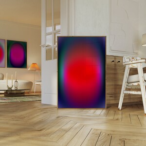 May include: A framed abstract art print with a red, pink, and blue gradient. The print is hanging on a white wall in a modern living room.