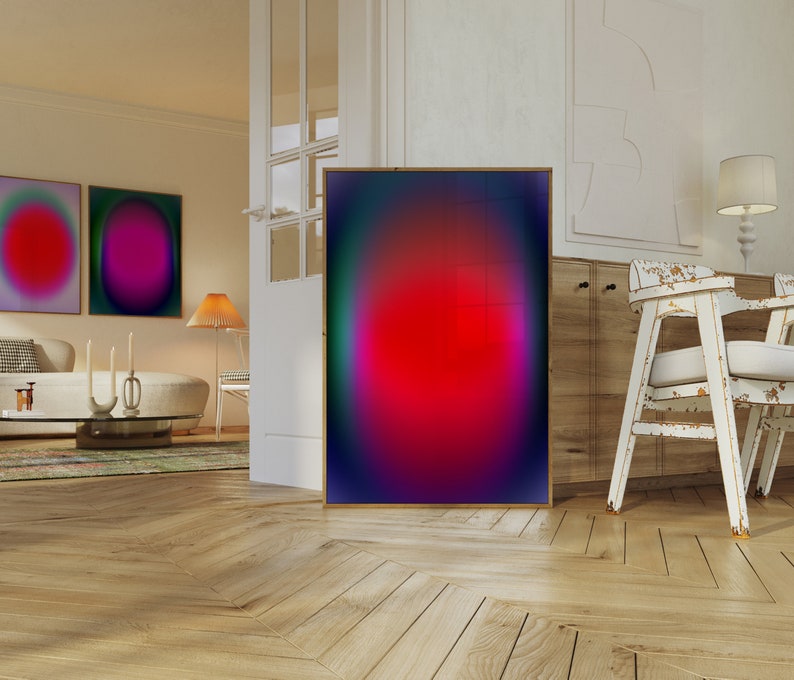 May include: A framed abstract art print with a red, pink, and blue gradient. The print is hanging on a white wall in a modern living room.