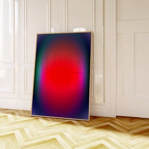 May include: Abstract art print with a red, pink, and purple gradient in a black frame. The print is hanging on a white wall in a room with wood floors.