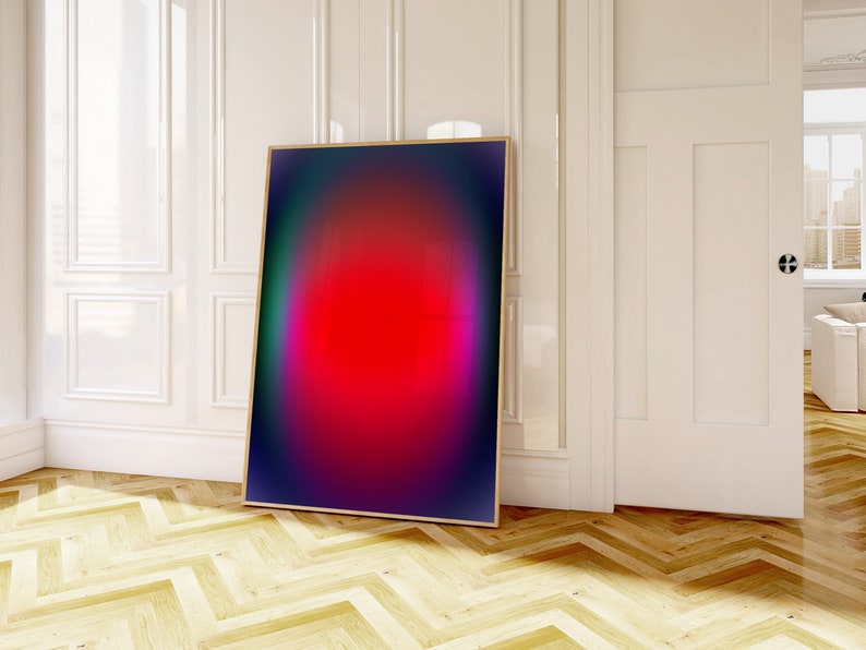 May include: Abstract art print with a red, pink, and purple gradient in a black frame. The print is hanging on a white wall in a room with wood floors.