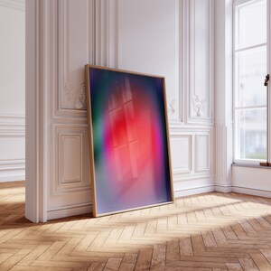May include: A framed abstract art print with a blurred, colourful design featuring shades of pink, purple, blue, and green. The print is leaning against a white wall in a room with wood floors.