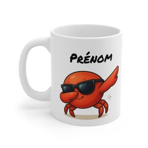 Peut inclure: Mug en céramique blanche avec un crabe de dessin animé portant des lunettes de soleil noires et faisant un dab. Le crabe est rouge avec un visage souriant. Le mot "PRÉNOM" est imprimé en noir au-dessus du crabe.