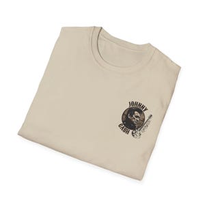 May include: A beige t-shirt with a black and white image of Johnny Cash and a guitar on the front. The image is in a circle with the words "Johnny Cash" around it.