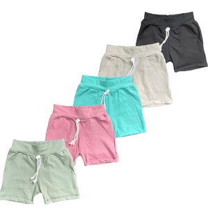 May include: Five pairs of women's shorts in different colors: black, beige, turquoise, pink, and light green. The shorts have a drawstring waist and side pockets.