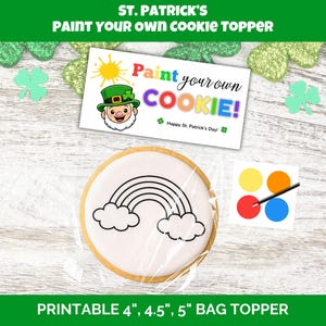 Può includere: Un kit per decorare biscotti per il giorno di San Patrizio. Il kit include un biscotto rotondo con un contorno arcobaleno, una tavolozza di colori e una carta con la scritta "Paint your own COOKIE!" con un'illustrazione di leprecauno.